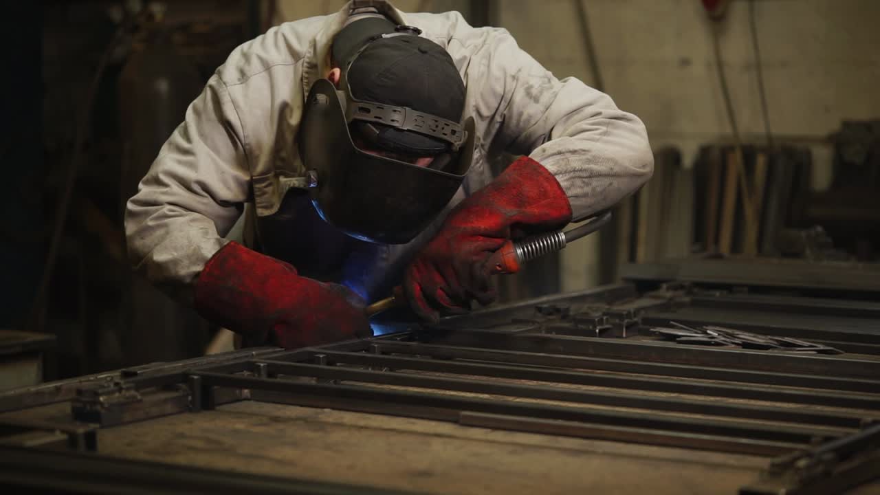 Sveiser som arbeider med metallport eller ramme