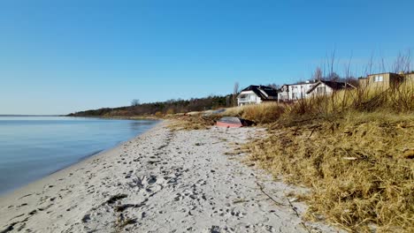 calmly rippling water from the clear blue lake on a small sandy beach with huge luxury villas with beautiful views on a clear summer day in poland