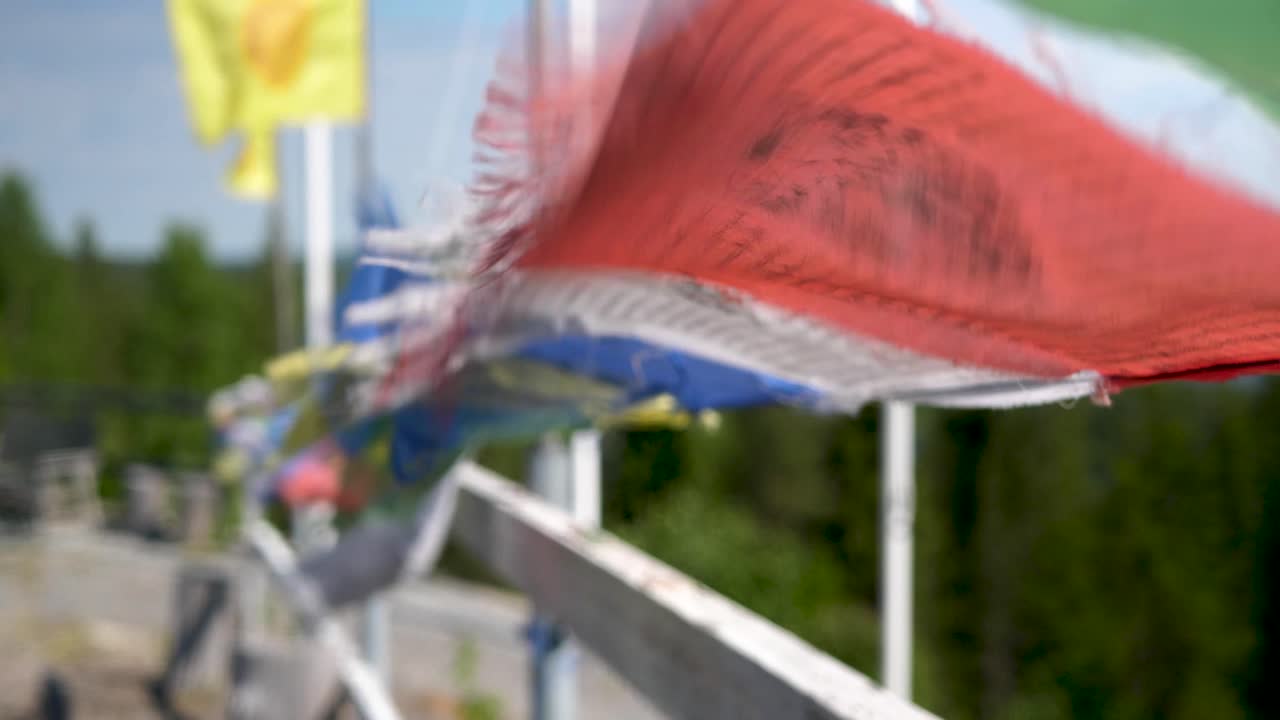 closeup of buddhist Prayer Flags Blowing in the wind, turist walking by in the distance.
