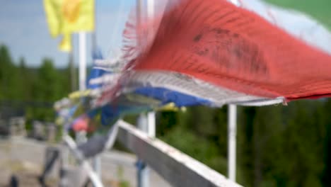 closeup of buddhist prayer flags blowing in the wind, turist walking by in the distance.