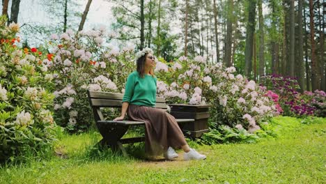 peaceful scene as woman in flower crown sits among rhododendrons, summer latvia