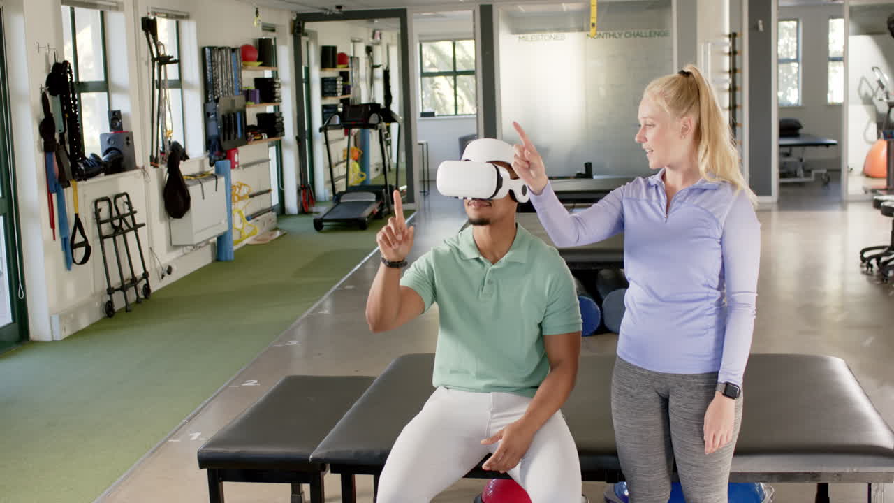 Using VR headset, man in rehab guided by therapist in rehabilitation center