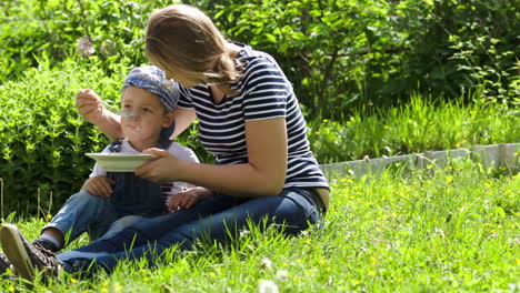 Mother-feeding-her-son-outdoor-on-a-summer-day