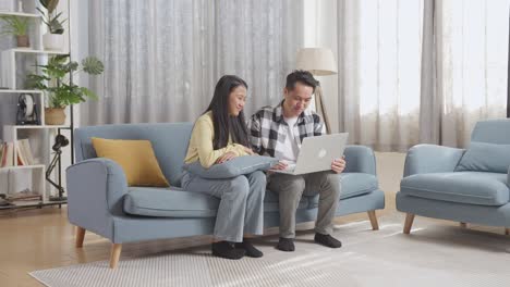 couple relaxing on couch watching laptop