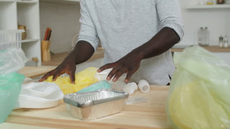 hombre negro clasificando residuos para su reciclaje en casa