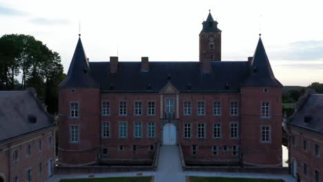 Vista-Aérea-De-La-Entrada-Y-El-Jardín-Del-Castillo-De-Alden-Biesen-En-Bélgica,-Alemania,-Repartidos-En-Una-Gran-área-Con-Vegetación-Y-Paisaje-Y-Carpa-Fuera-De-La-Entrada-Principal-Durante-El-Día