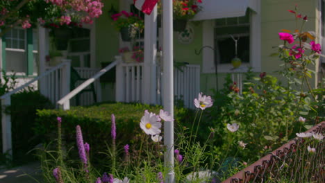 tilt-up on a flag pole with an american flag, with flowers in the garden on a sunny day