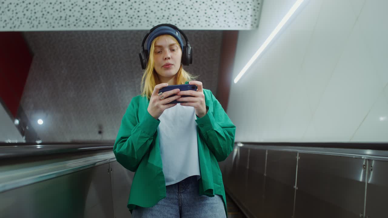 A woman playing a mobile game on an escalator
