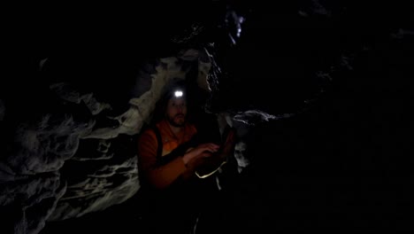 male hiker exploring a dark cave 4k