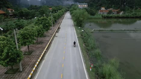 cool aerial tilting shot following bike on a asian road sounded my water and stunning green mountains