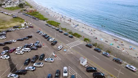 escena de playa concurrida durante los fines de semana que muestra los autos estacionados en la carretera a lo largo de la playa de nantasket, massachusetts, ee.uu.