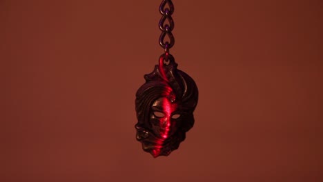 close up of the metal venetian mask souvenir keychain and the vertical laser light