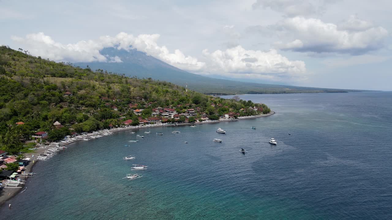 vista aérea cinematográfica de la ciudad costera balinesa amed beach con el monte agung en la distancia