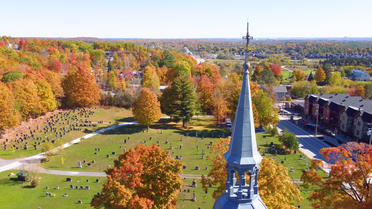Historic church steeple, cemetery surrounded by vivid fall trees, Estrie, Québec