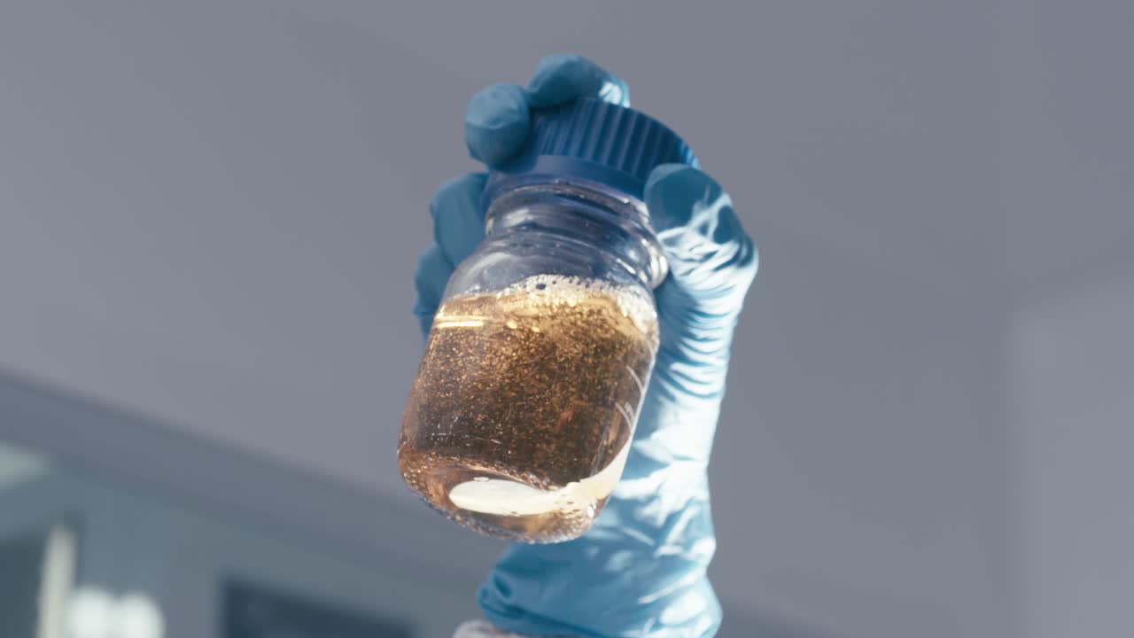 Lab Worker shake a Test Tubes containing chemical liquids while working in a Modern Research