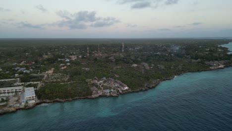 Town-of-Kusini-beach-in-East-Zanzibar-Island-Tanzania-Africa-with-communication-towers-in-view,-Aerial-flyover-shot