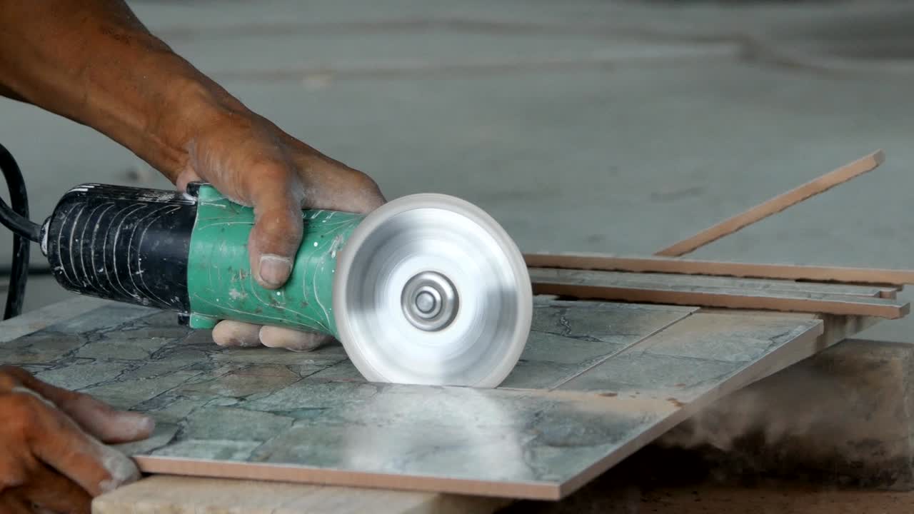trabajador cortar una baldosa con una amoladora angular en el sitio de construcción