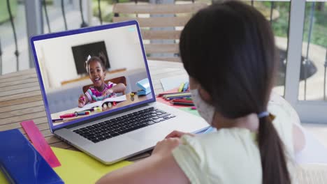 Mixed-race-girl-sitting-at-desk-using-laptop-having-online-school-lesson