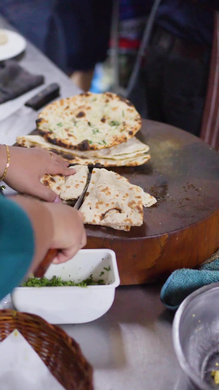 Chef Cutting Fresh Naan Bread on Wooden Board in Restaurant Kitchen