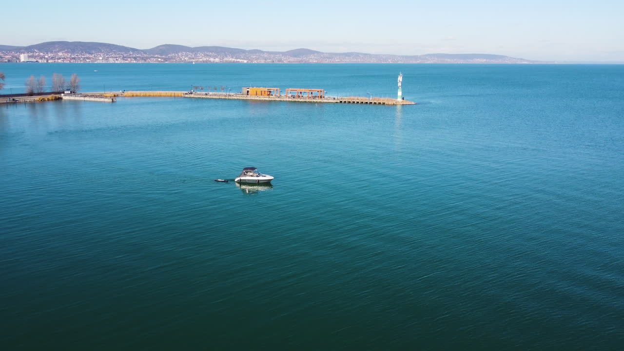 Drone view of Kis Mohle pier extending into blue water at Lake Balaton on clear sunny day