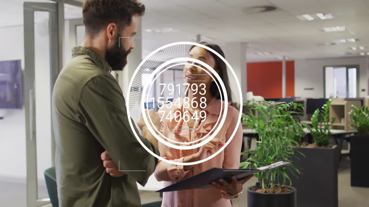 coworkers discussing business data with HUD overlay while using tablet and clipboard in office