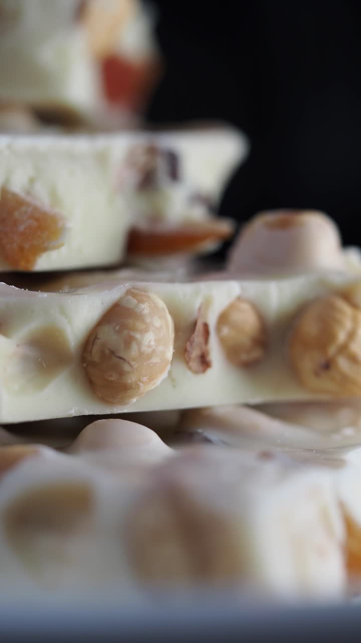 Primo piano di tavolette di cioccolato bianco impilate con nocciole