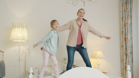 mother and daughter jumping on bed