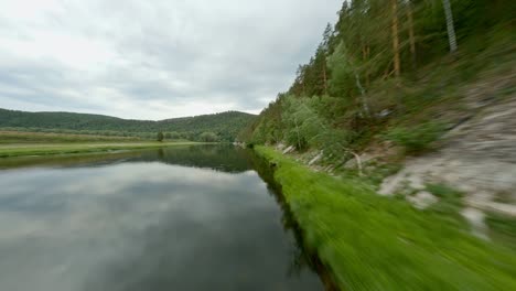 rocky mountain is densely overgrown with coniferous trees and shrubs. extensive natural lands. harmony of the environment. boats near the shore. shooting from the air.