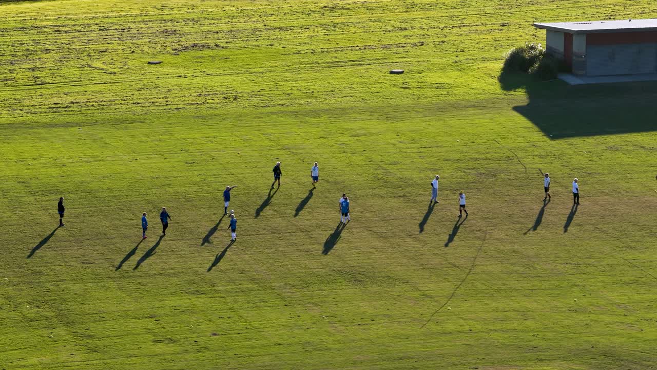 Aerial view of elderly players engaging in a soccer match on a sunny field, showcasing teamwork and fitness