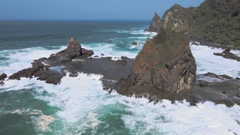 aerial view of huge coral rock on the beach hit by powerful sea waves