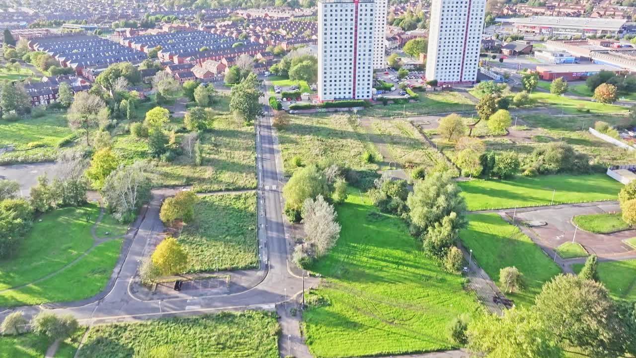 Ripresa aerea con drone di un'area di Manchester con un parco pubblico che vola in direzione di una zona residenziale con blocchi di case e appartamenti