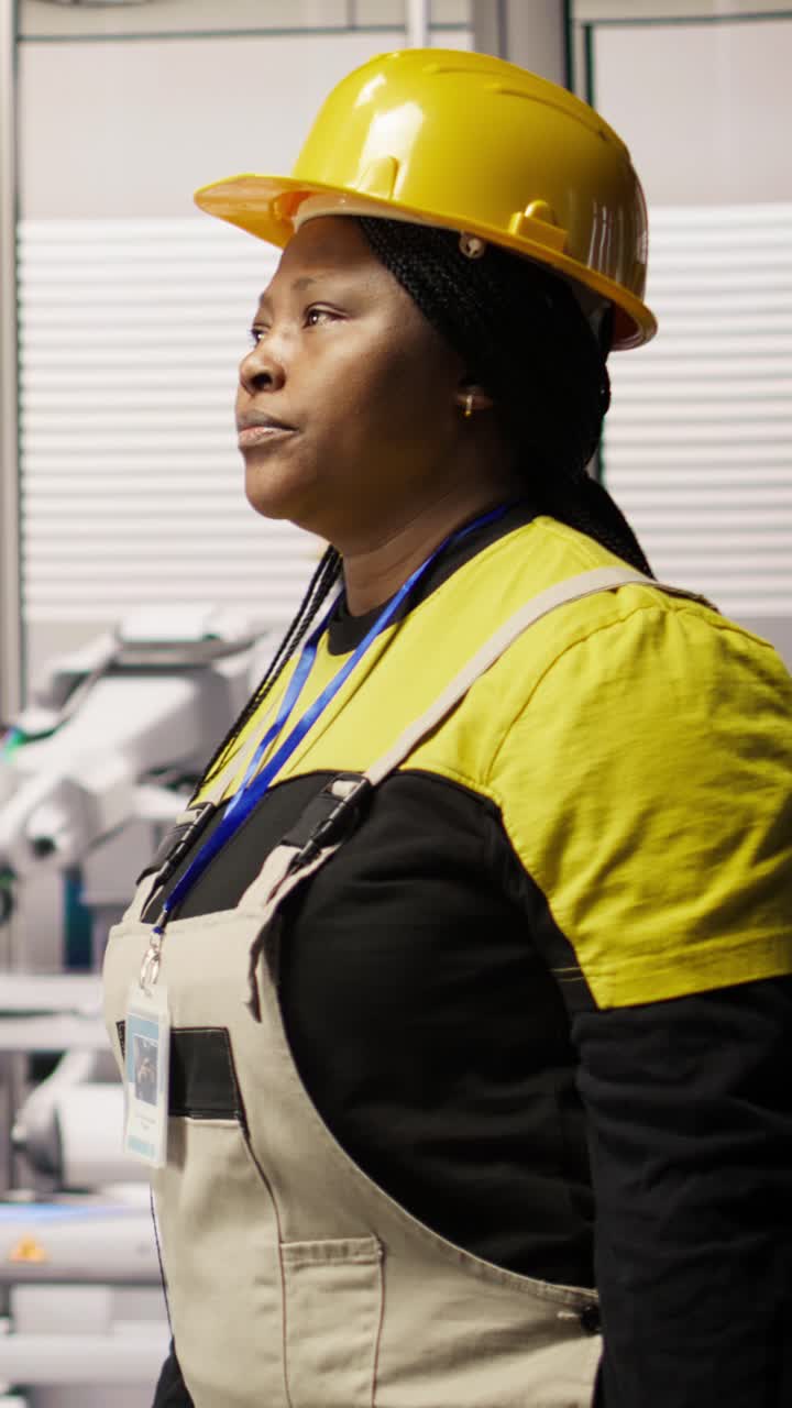 Vertical video Engineer in smart factory overseeing robotic assembly lines