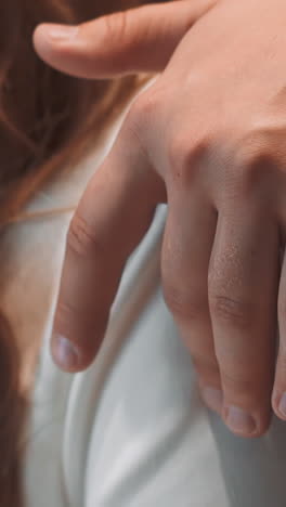 newlywed man in tuxedo strokes arm of bride in white dress at wedding ceremony closeup slow motion. marriage of elegant young couple. family event