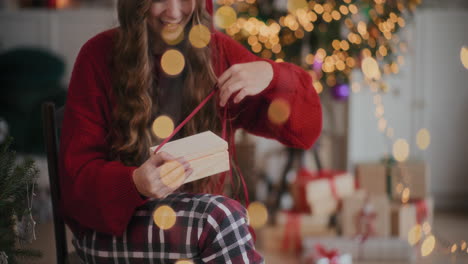 amazed woman opening illuminated wooden gift box at home during christmas