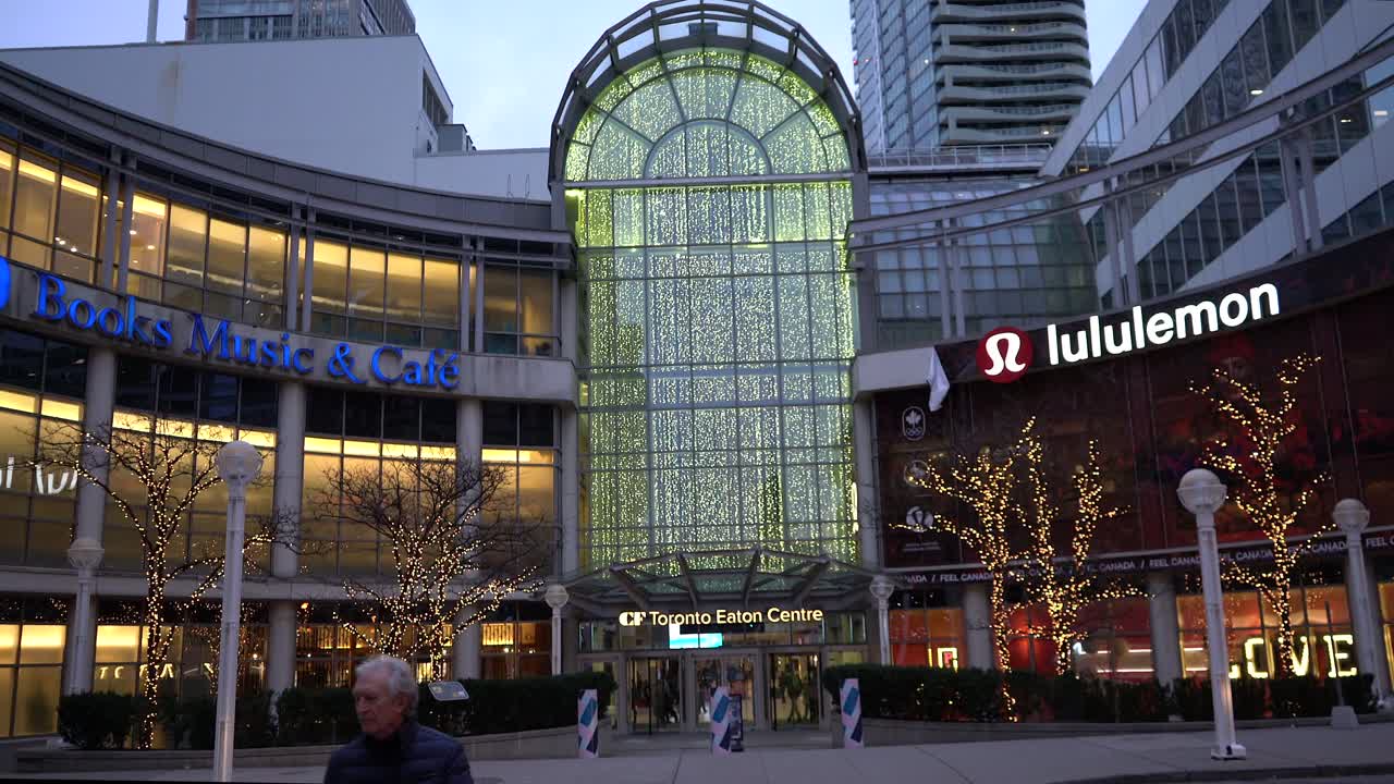 CF Toronto Eaton Centre side entrance near city hall with winter Christmas lights decorations on trees during winter evening