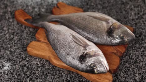 two fresh fish on a wooden cutting board