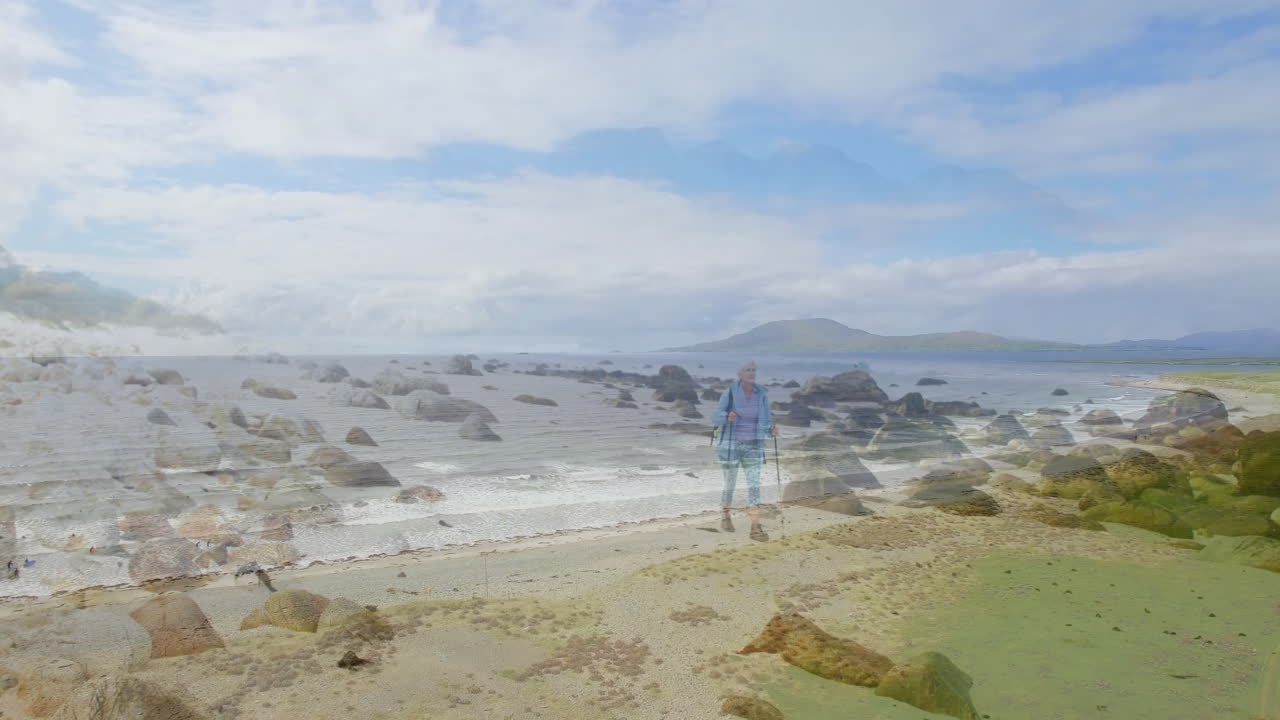 Senior female hiker trekking rocky beach, showing health tech heart icon and elevation graph