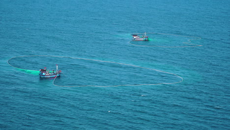 Toma-Estática-Aérea-De-Barcos-En-El-Mar-Azul-Haciendo-Pesca-Con-Red