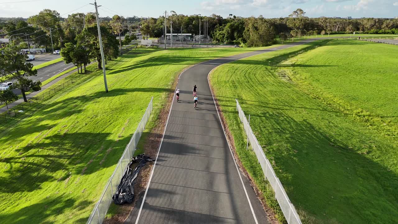 Cyclists ride along a winding track in Gold Coast, Australia. Captured with aerial drone footage during daylight, showcasing lush green surroundings