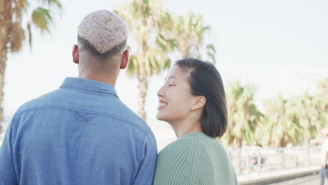 portrait of happy biracial couple on promenade, in slow motion