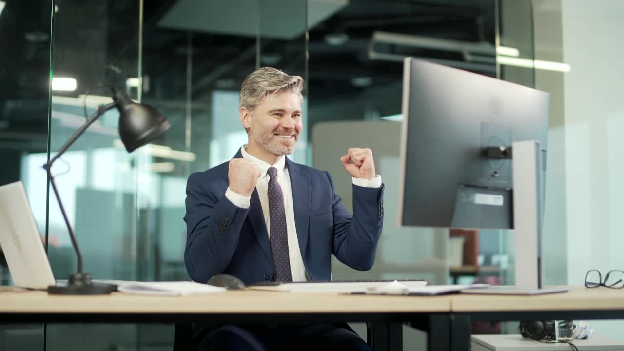Happy mature bearded Business Man Employee Working on pc computer Celebrates Successful YES Gesture. Working in moderm office Stroke of Luck, Wins Big