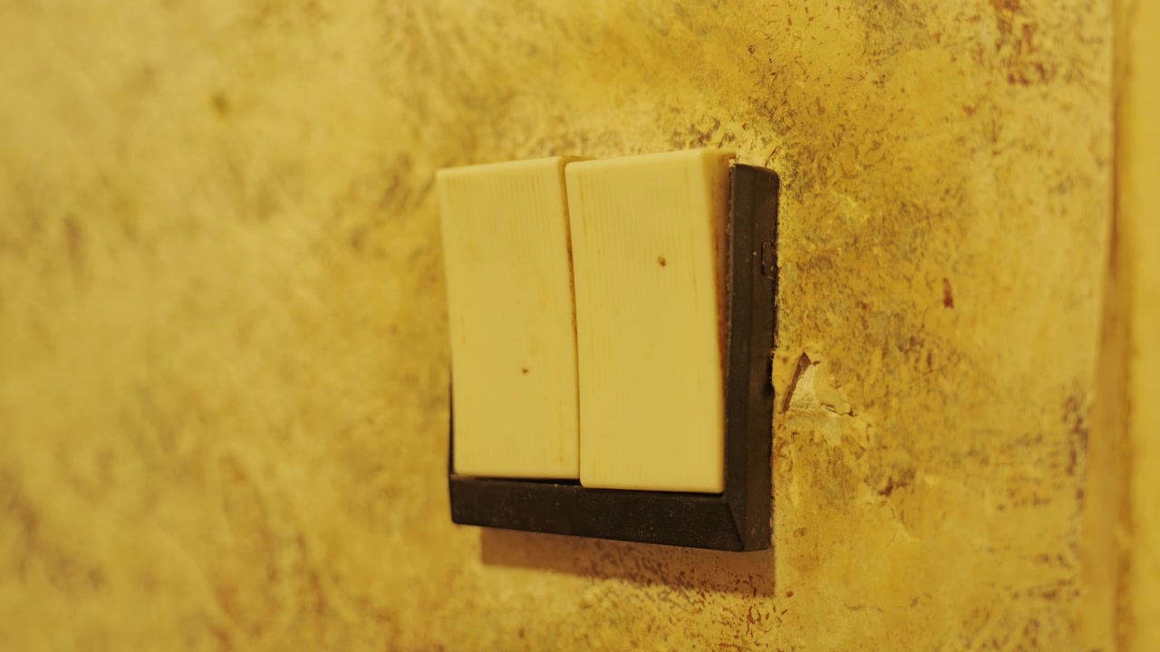 Aged double light switch on textured wall reflects timeless residential design.