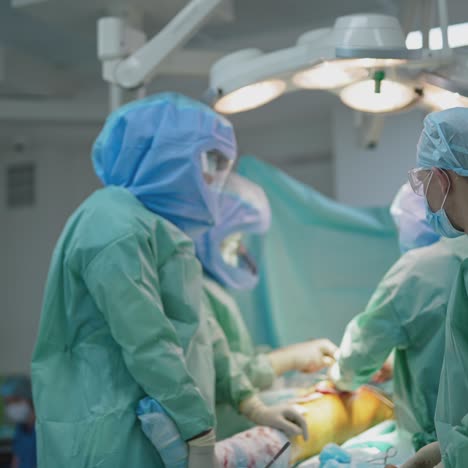 operation in surgical room. group of doctors in protective suits treating patient's leg in the operating room. surgery at pandemic. covid-19