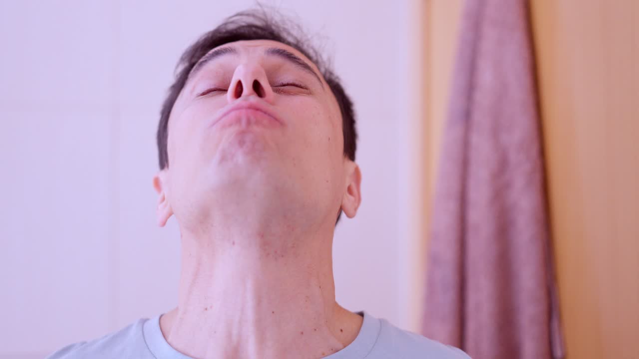 Man rinsing mouth with mouthwash in bathroom