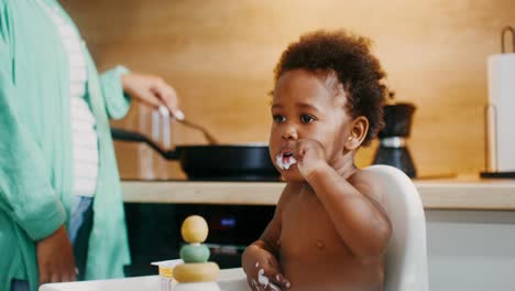 baby eating yogurt in highchair