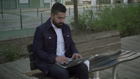 hombre enfocado usando computadora portátil en la calle