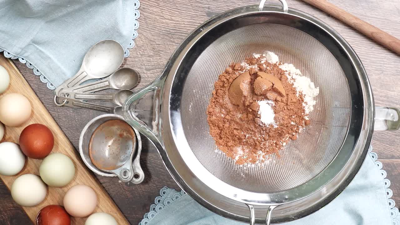 Baking delicious caramel pecan brownies. In a mixing bowl with a flour sifter adding flour and cocoa powder. Freshly baked gooey chocolate brownies with sweet caramel and nutty pecans.