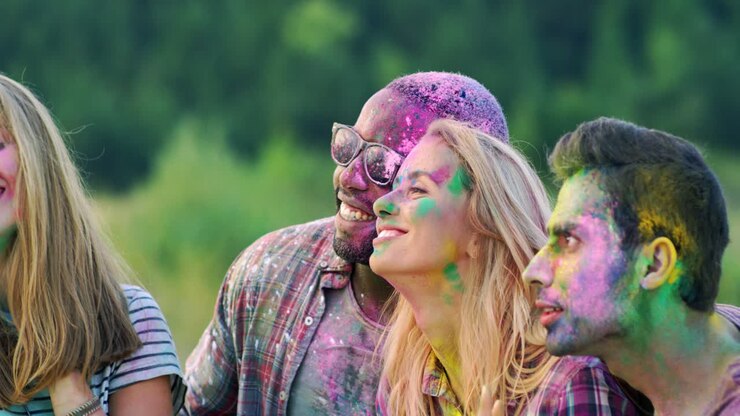 Close Up Of The Joyful Young Mixed Races Male And Female Friends Laughing And Celebrating Holi Holiday Outdoors While Posing To The Smartphone Camera And Taking Selfies Photos