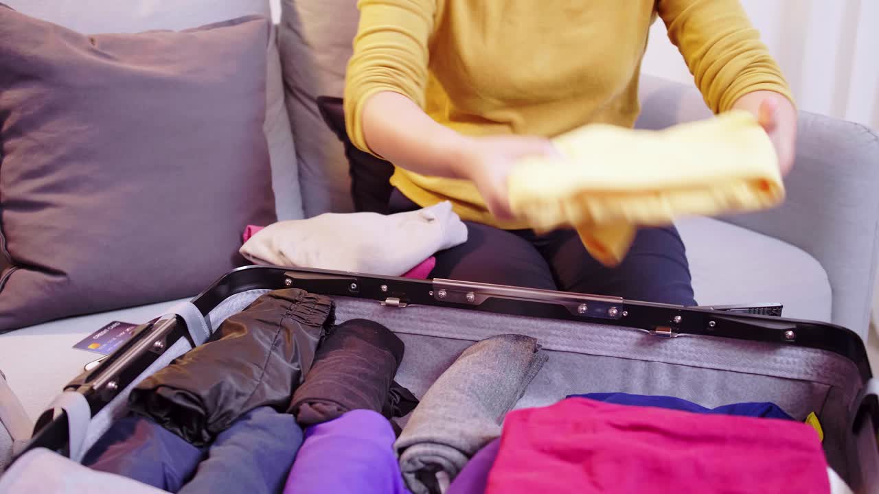 여행을 위해 옷을 들고 가방을 준비하는 여자