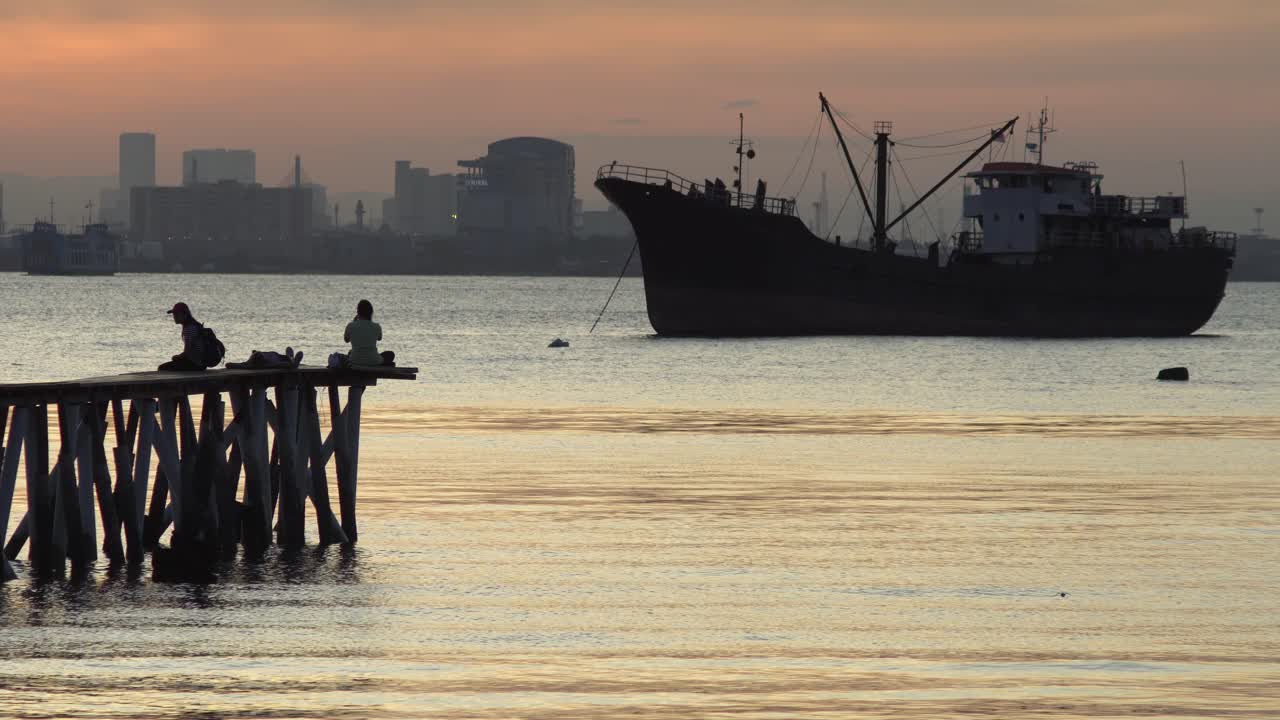 실루 ⁇  관광객 은 타인 제티 의 나무 다리 에 앉아 있다